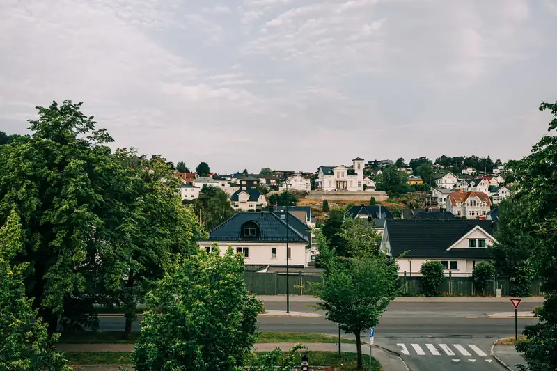 Et boligstrøk med eneboliger og hager, med en vei og et fotgjengerfelt i forgrunnen
